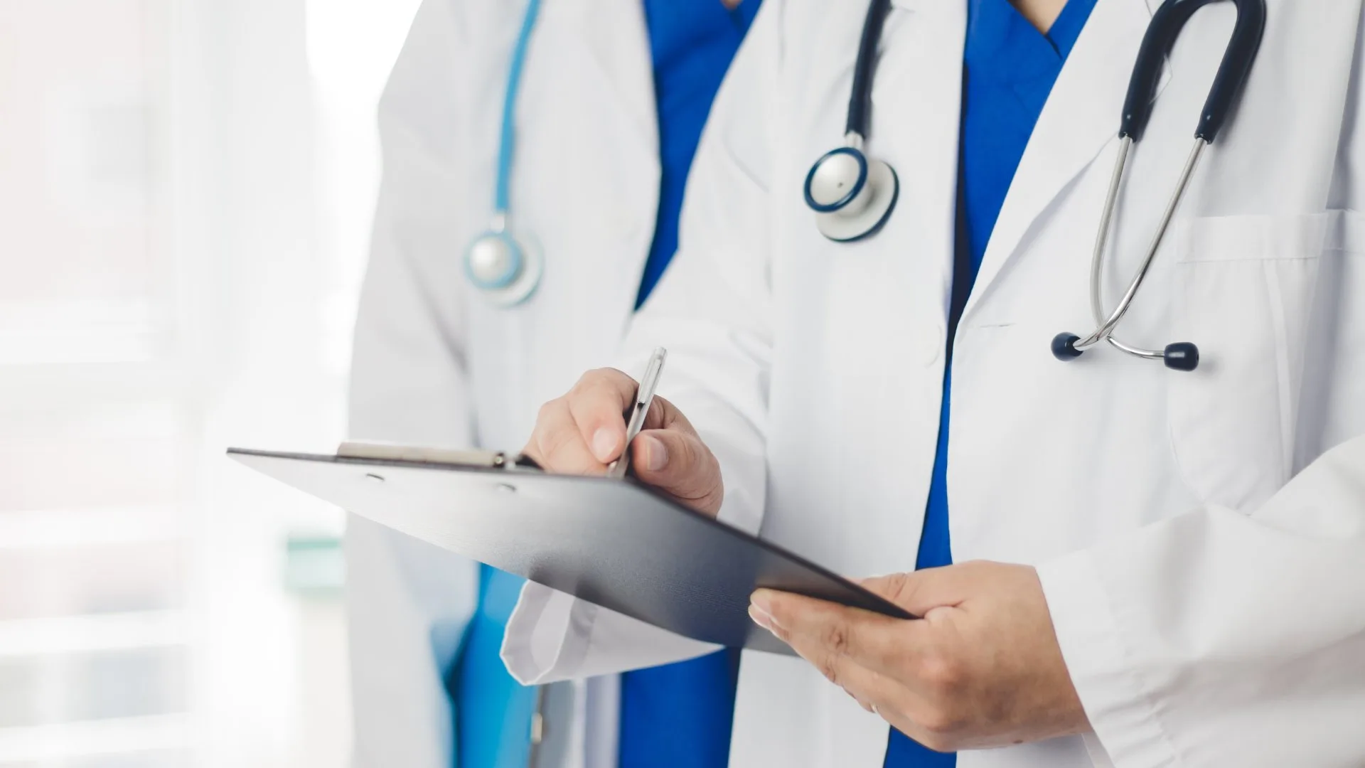 Médicos com uniforme hospitalar padronizado conforme ANVISA – São Paulo Médicos com jaleco branco e estetoscópio em conformidade com normas ANVISA para uniformes hospitalares em SP